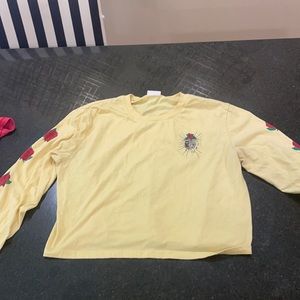 This is a long cropped yellow shirt with roses